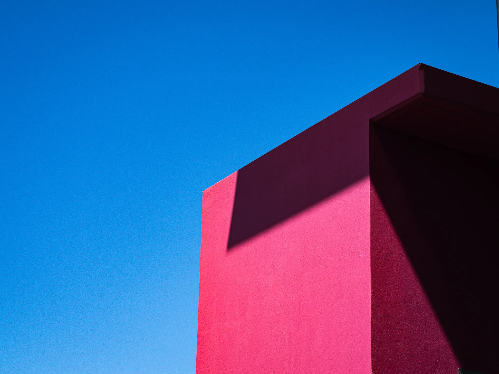 Magenta building corner against a clear blue sky